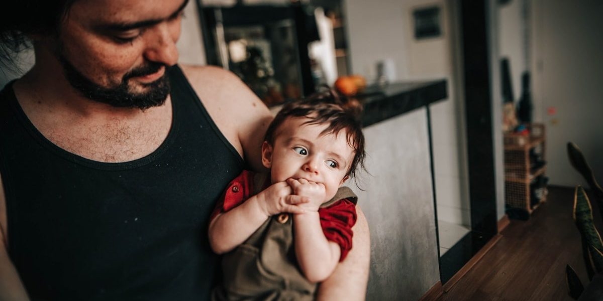 man in black tank top sitting beside boy in red tank top