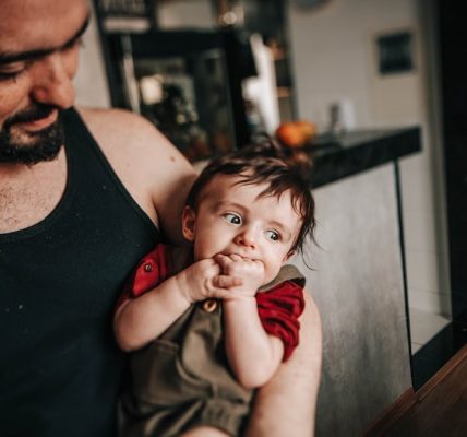 man in black tank top sitting beside boy in red tank top