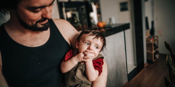 man in black tank top sitting beside boy in red tank top