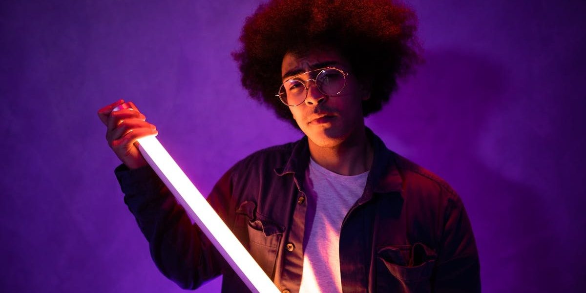 Portrait of a stylish young adult holding a neon light with vibrant, artistic vibes.