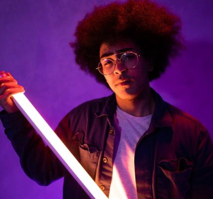 Portrait of a stylish young adult holding a neon light with vibrant, artistic vibes.